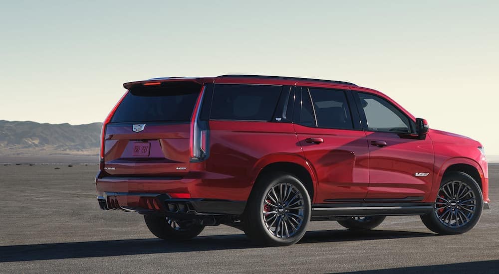 A red 2024 Cadillac Escalade V is shown from the rear at an angle after leaving a Cadillac dealer in Highland Township.